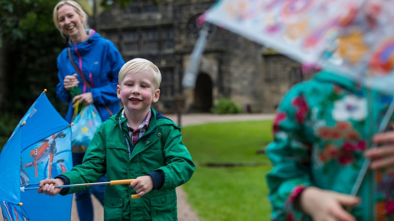 Child and adult with open umbrellas running in the rain.